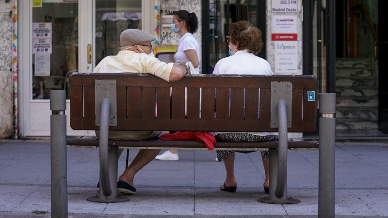 Una pareja de ancianos con mascarilla sentada en un banco en Madrid. E.P./A. Pérez Meca