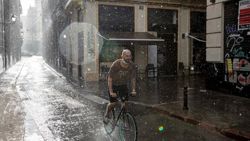 Una persona circula en bicicleta bajo una fuerte tromba de agua en València.