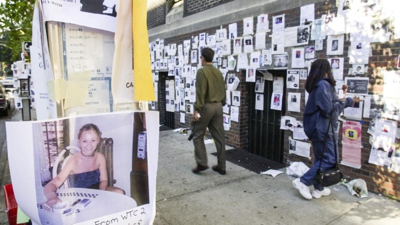 Un hombre y una mujer pasan junto a una pared llena de carteles de los desaparecidos tras el ataque al World Trade Center en Nueva York el 11-S. EFE / EPA / TANNEN MAURY