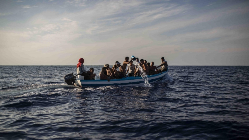 Un grupo de 17 jóvenes tunecinos achican agua de la patera en la que navegan hacia Lampedusa (Italia) escoltadas por el buque Astral de Open Arms, este miércoles.