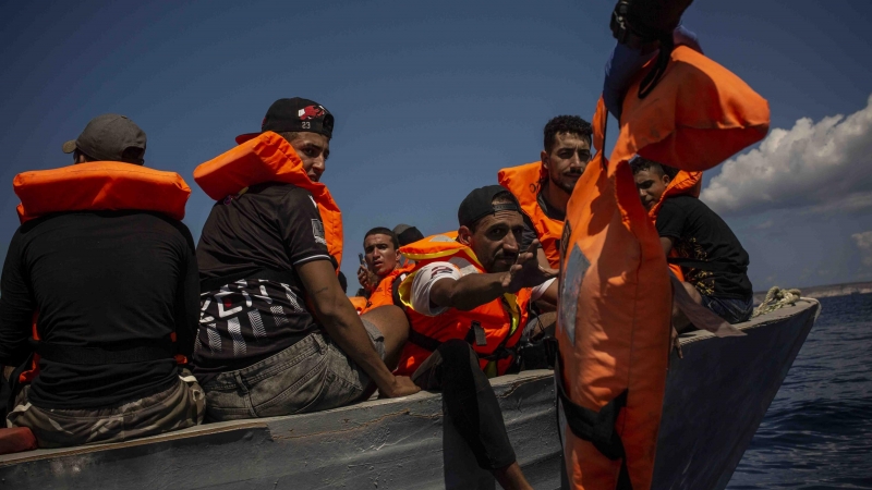 Un grupo de migrantes tunecinos reciben chalecos salvavidas de los socorristas de Open Arms a cuatro millas al sur de Lampedusa (Italia)