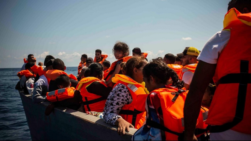 Una niña a bordo de la patera sonríe cuando llegan los socorristas de Open Arms para facilitarles chalecos salvavidas mientras son rescatados por la Guardia Costera italiana.