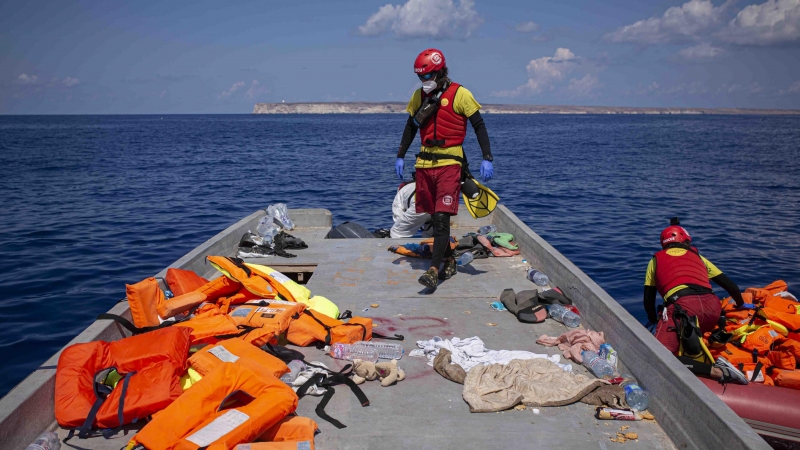 Un socorrista de Open Arms recorre la patera después del rescate de las 72 personas para recoger los chalecos salvavidas.