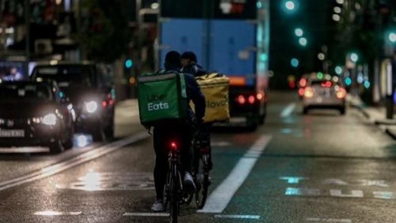 Foto de archivo. Un rider de Uber Eats y de Glovo circulan por las calles de Madrid.