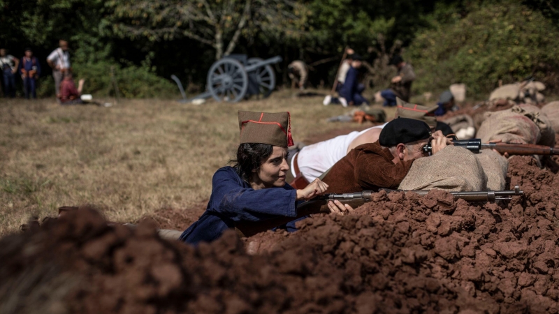 1. Una voluntaria, representando el papel de miliciana, carga su fusil tras un parapeto durante una representación de batalla del frente del salón 36/37 en Grullos, Asturias, 11 de Septiembre, 2021.