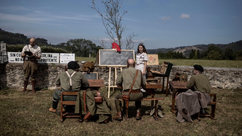 Voluntarios representando el papel de soldados (alumnos) y profesora en uno de los espacios de representación de las chámpalas de alfabetización llevadas a cabo por el ejercito leal a la República durante la guerra (36/39) Grullos, Asturias, 11 de Septiem