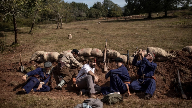 Voluntarios uniformados de diferentes unidades republicanas que participaron en el frente del Nalón toman cobertura en un parapeto durante la representación de una batalla de trincheras. Grullos, Asturias, 11 de Septiembre, 2021.