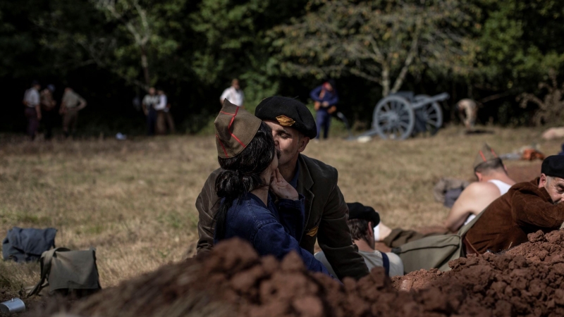 Voluntarios representando milicianos leales a la republica se besan durante un descanso en la representación de la batalla. Grullos, Asturias, 11 de Septiembre, 2021.