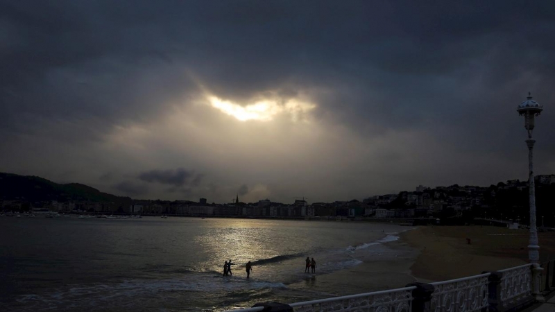 Varias personas en la playa de Ondarreta de San Sebastián, donde los cielos de Euskadi se presentan nubosos y con chubascos.