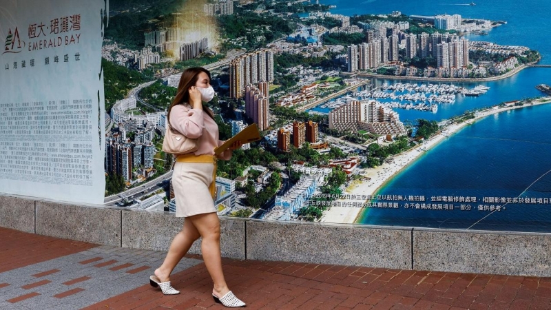 Una mujer pasa junto a un anuncio de Emerald Bay, una de las promociones de China Evergrande, en Hong Kong. REUTERS/Tyrone Siu