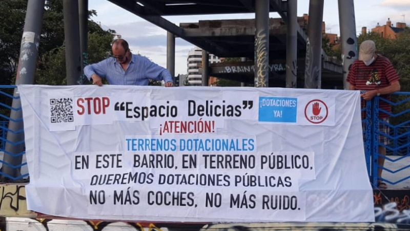 Dos vecinos de Madrid colocan una pancarta contra el macroproyecto 'Espacio Delicias'.