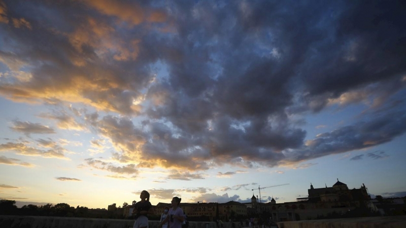 Varias personas caminan sobre el puente romano en Córdoba.