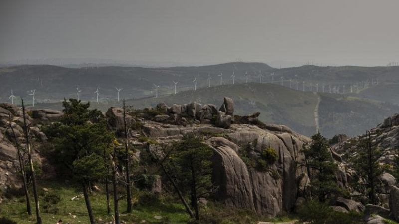 Una familia come en el área recreativa del Monte Pindo, con los molinos al fondo en las montañas.