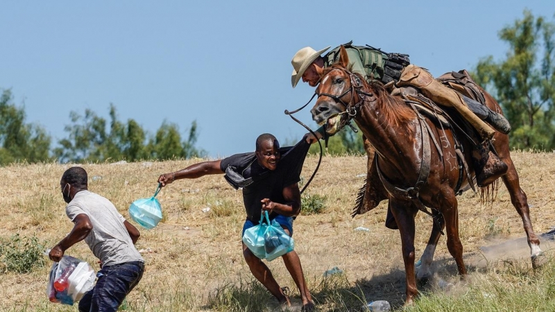 Un agente de la patrulla fronteriza de Estados Unidos a caballo intenta detener a dos migrantes haitianos en el río Grande (Texas).