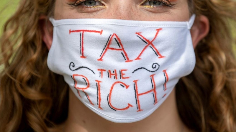 Una activista con una mascarilla en la que lleva escrito el lema  'Tax the rich' ('Impuestos para los ricos'). REUTERS/Nick Iwanyshyn