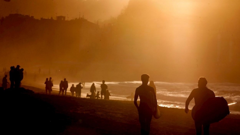 Surfistas y personas pasean por la playa de la Zurriola de Donosti.