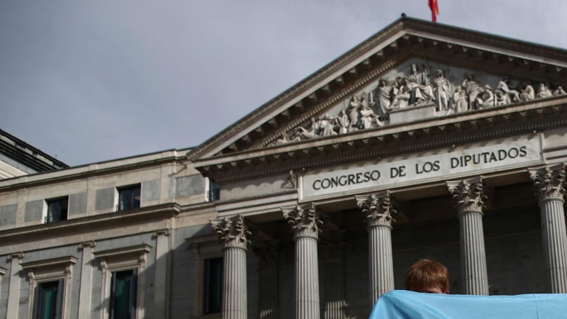 Dos personas sostienen una bandera trans durante una concentración convocada frente al Congreso de los Diputados en Madrid (España). Foto de archivo.