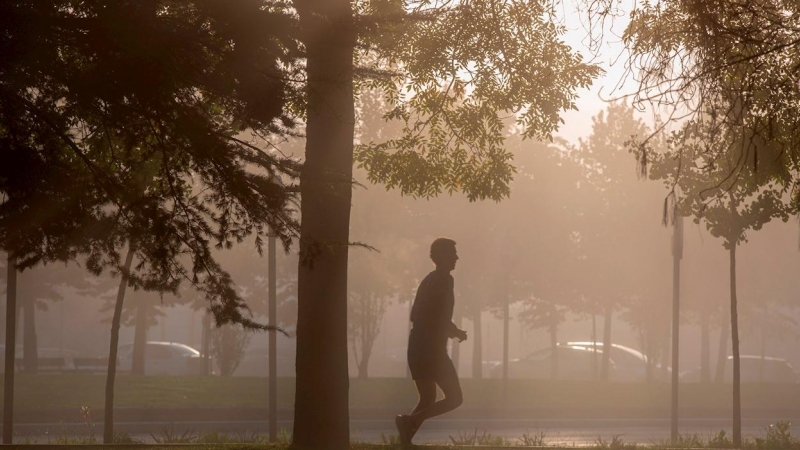Un hombre corre entre la neblina por la mañana en Vitoria.