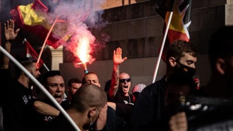 Jóvenes neonazis con bengalas levantan el brazo durante una manifestación neonazi para celebrar el día de la Hispanidad, a 12 de octubre de 2021, en Barcelona.