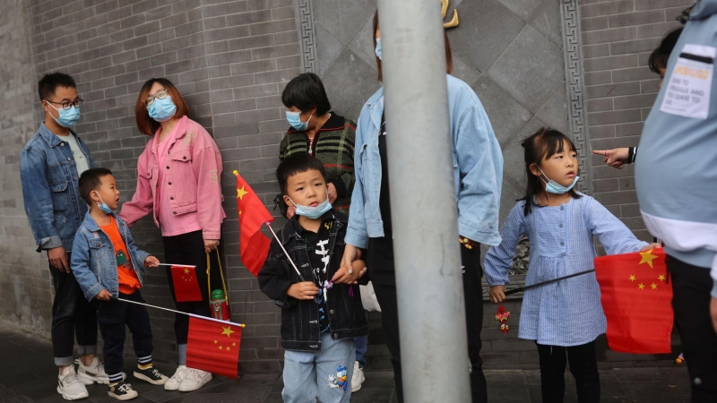 05/10/2021 Los niños sostienen banderas chinas cerca de la Ciudad Prohibida durante las vacaciones del Día Nacional tras un brote de la enfermedad por coronavirus