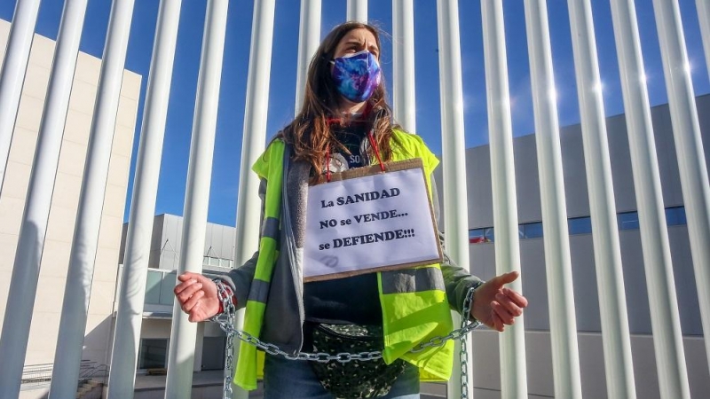Una trabajadora sanitaria sujeta un cártel en el que se lee: 'La sanidad no se vende, se defiende'.