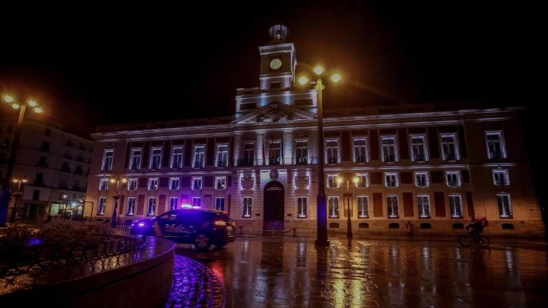Un coche de la Policía Nacional circula en la Puerta del Sol durante la primera noche de toque de queda en Madrid