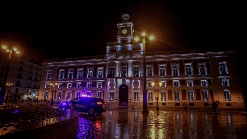 Un coche de la Policía Nacional circula en la Puerta del Sol durante la primera noche de toque de queda en Madrid