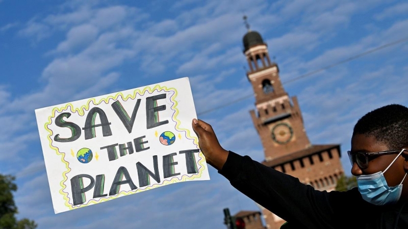 Un joven activista de Fridays For Future muestra una pancarta con el lema 'Salvemos el planeta' en Milán, en una protesta previa a la COP26 de Glasgow.
