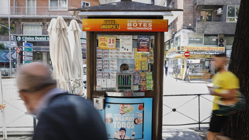 Dos personas pasan junto al quiosco de la ONCE, en Madrid. E.P./Jesús Hellín