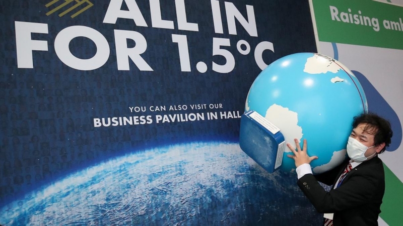 Una persona carga con un globo terráqueo durante la Cumbre del Clima de Glasgow (COP26).