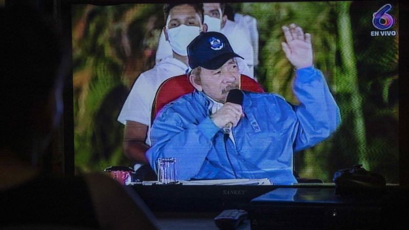 Una mujer observa en el televisor al presidente de Nicaragua Daniel Ortega durante el acto en homenaje al 45 aniversario de la muerte de Carlos Fonseca Amador.