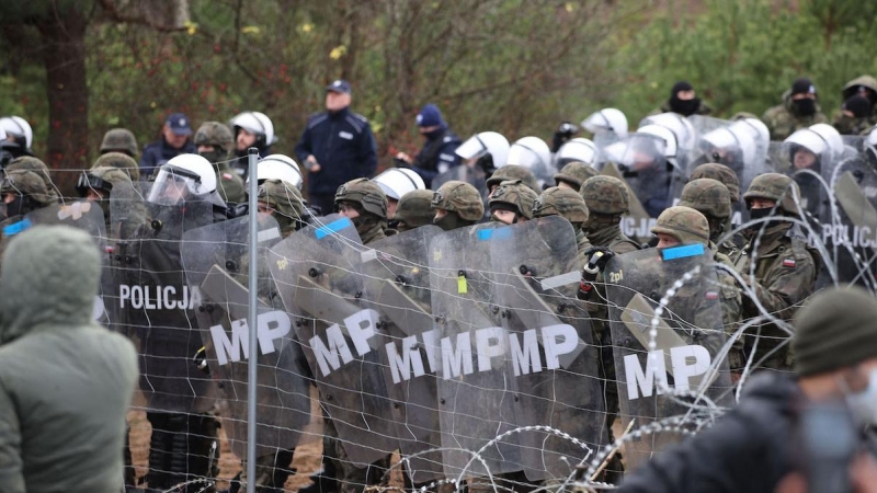 Una fotografía tomada el 8 de noviembre de 2021 muestra a agentes polacos observando a los migrantes en la frontera con Bielorrusia.