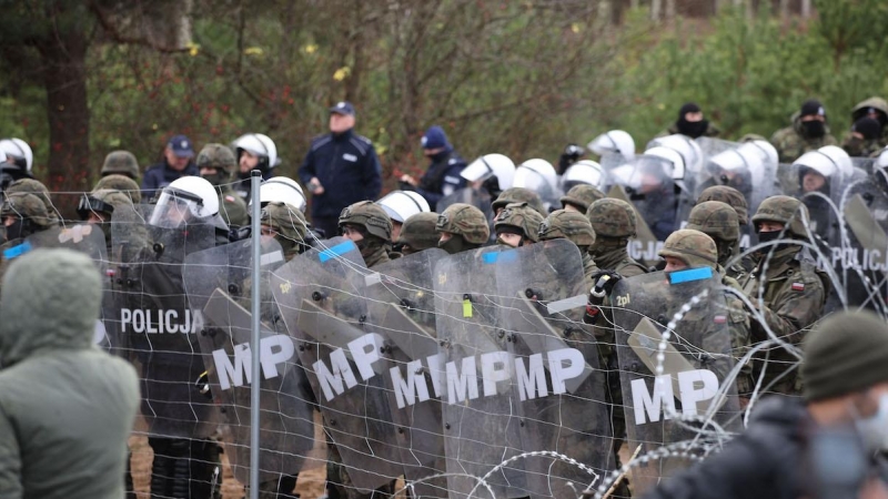 Una fotografía tomada el 8 de noviembre de 2021 muestra a agentes polacos observando a los migrantes en la frontera con Bielorrusia.