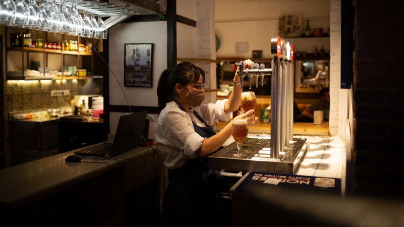 Una camarera sirve una cerveza en el interior de un bar en una calle céntrica de Barcelona