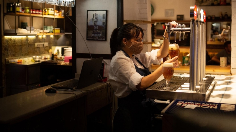 Una camarera sirve una cerveza en el interior de un bar en una calle céntrica de Barcelona