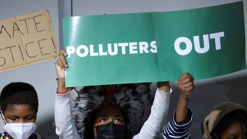 Los manifestantes protestan con pancartas en la Conferencia de las Naciones Unidas sobre el Cambio Climático de Glasgow, la COP26.