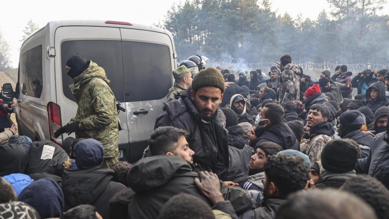 Refugiados y migrantes se agolpan para recibir ayuda humanitaria distribuída por soldados bielorrusos en un campo en la frontera con Polonia en la región de Grodno.