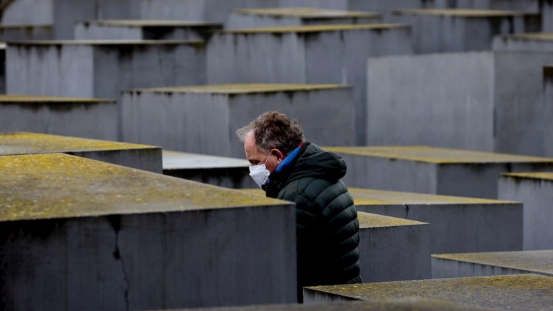 Un hombre con una mascarilla camina entre las estelas del llamado memorial del Holocausto.