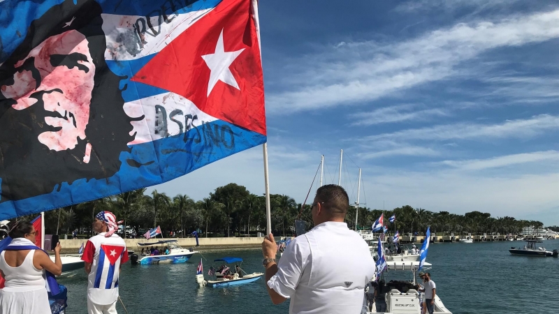 Un manifestante ondea hoy una bandera cubana con la imagen del Che Guevara y la palabra 'Asesino', en la dársena situada en la bahía de Vizcaya en Miami.