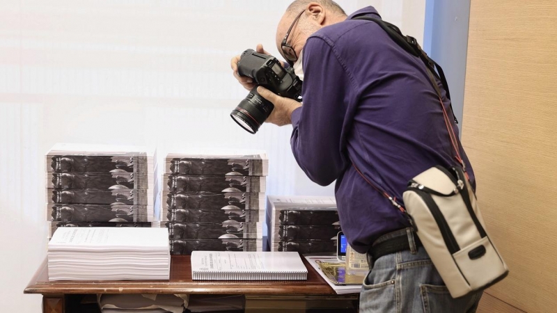 Un fotoperiodista realiza una fotografía a varios tomos de las enmiendas presentadas a los Presupuestos del Estado para 2022, en la Comisión de Presupuestos. E.P./Eduardo Parra