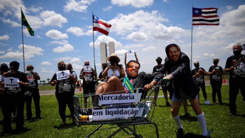 Manifestantes con máscaras que representan al presidente brasileño Jair Bolsonaro y Arthur Lira, presidente de la Cámara Baja de Brasil, participan en una protesta en Brasilia el 30 de octubre de 2021.