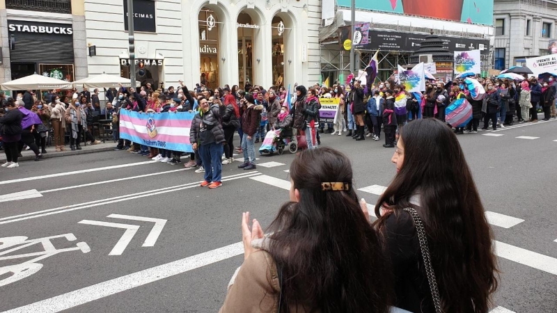 Dos transeúntes aplauden a los manifestantes a favor de la ley trans en la Gran Vía de Madrid.