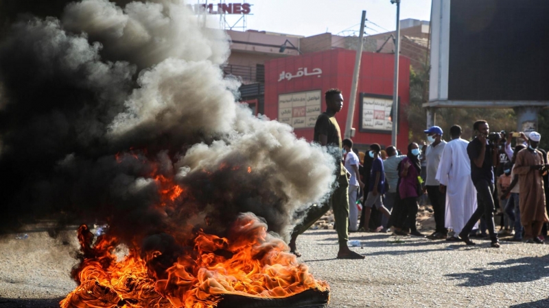 Sudaneses se reúnen cerca de objetos en llamas durante una protesta contra el golpe militar en Jartum.