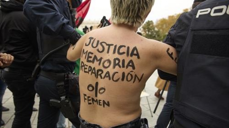 Policías nacionales sujetan a una activista de Femen que protesta frente a una concentración franquista