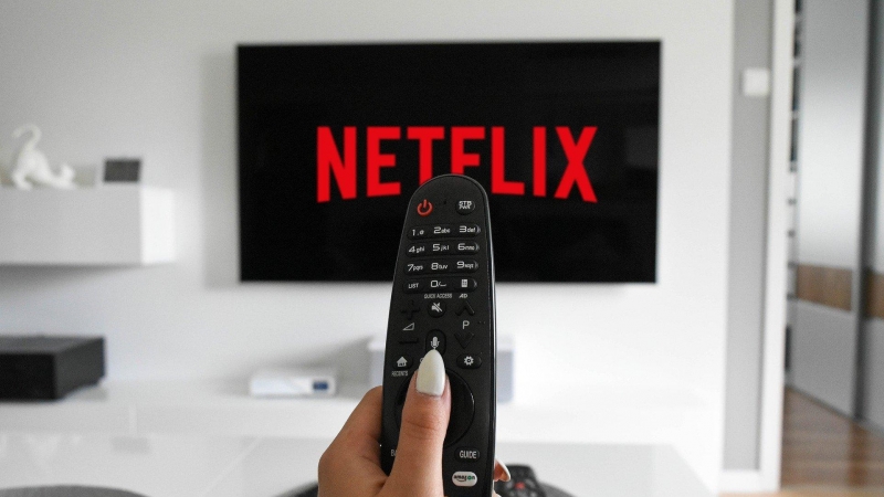 Mando de televisión apuntando a una pantalla donde aparece el logo de Netflix.