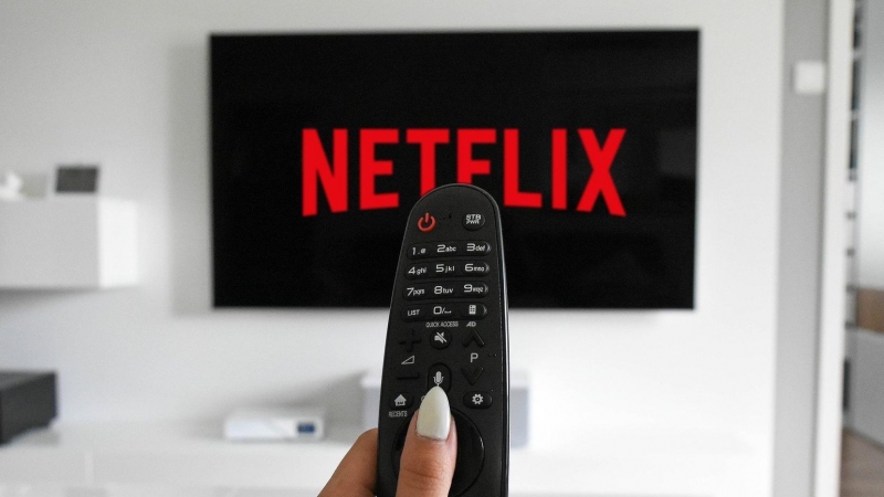 Mando de televisión apuntando a una pantalla donde aparece el logo de Netflix.