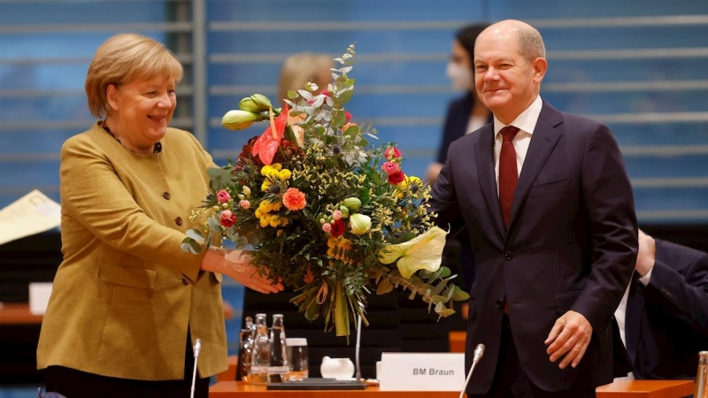 La canciller interina Angela Merkel recibe un ramo de flores del ministro de Finanzas y vicecanciller interino Olaf Scholz.