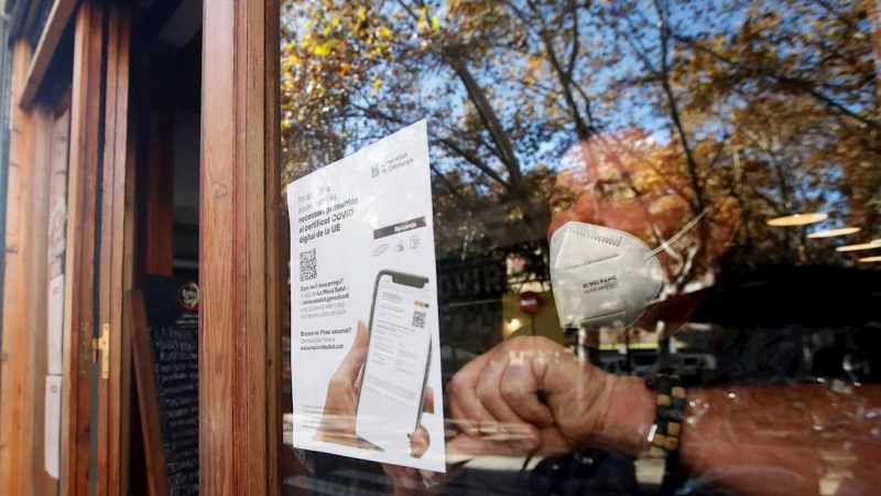 26/11/2021.- El responsable de un bar del barrio de Gracia de Barcelona cuelga un cartel avisando a sus clientes de la necesidad de presentar el certificado de vacunación para entrar en el local.