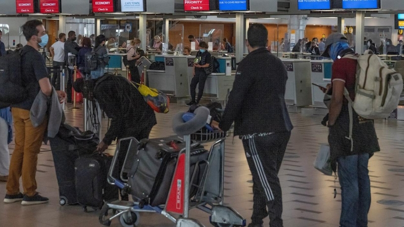 Varios pasajeros miran las pantallas de información en el aeropuerto de Ciudad del Cabo, en Sudáfrica.