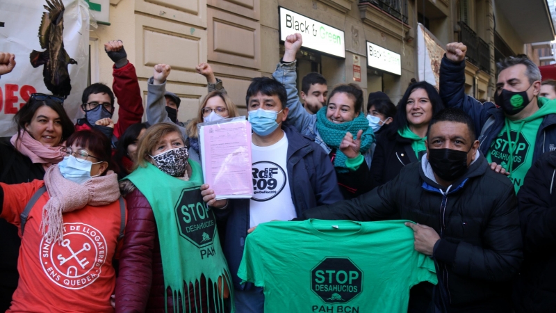 El Carlos, envoltat d'activistes pel dret a l'habitatge, mostrant el paper de suspensió del desnonament que l'afectava, aquest 3 de desembre de 2021.